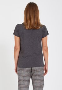 T-shirt à manches courtes gris charbon, texture douce, encolure ronde, associé à un pantalon à motifs à carreaux en gris, blanc et noir.