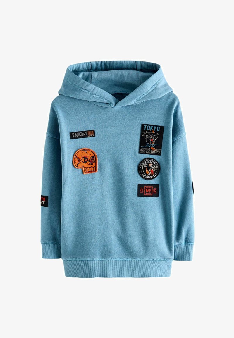 Helle blaue Kapuzenpullover mit verschiedenen Patches, darunter ein Totenkopf und Text-Patches. Mit Kängurutasche und gerippten Bündchen.