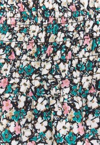 Blommig tyg med svart bakgrund och vita, gröna och rosa blommor. Materialet har en veckad textur med samlade detaljer.