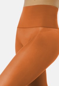 Legginsy o wysokim stanie, bezszwowe, w kolorze pomarańczowym, wykonane z elastycznego materiału o gładkiej fakturze i dopasowanym kroju.