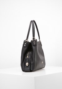 Mustat nahkakäsilaukku, jossa on kuvioitu pinta, varustettuna vetoketjullisella sivutaskulla, kahdella kahvalla ja kullansävyisillä yksityiskohdilla.