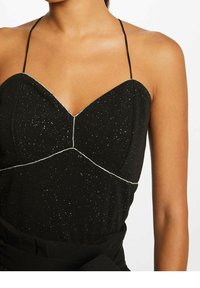 Vestido negro con un corsé ajustado, escote en forma de corazón, tirantes delgados, costuras plateadas y una tela texturizada con sutiles destellos.