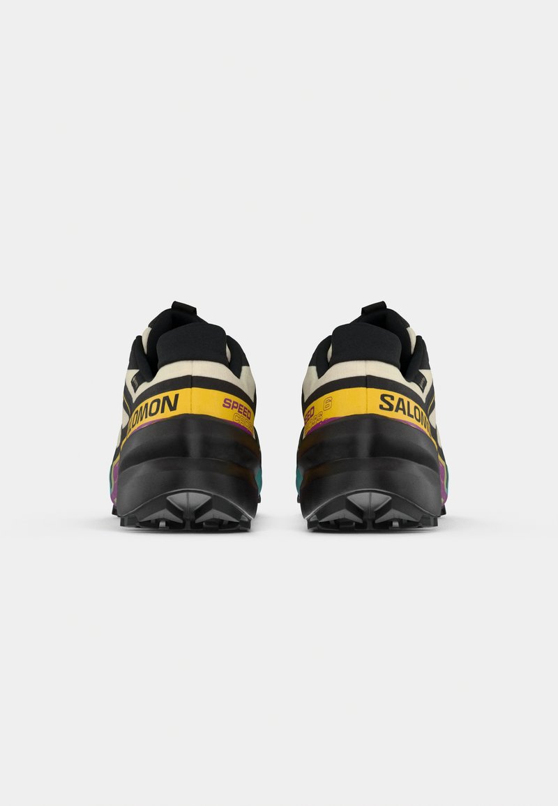 Trailrun schoenen in zwart, off-white, geel en paars. Beschikt over een rubberen zool met hoge grip en een gevoerd kraag voor comfort.
