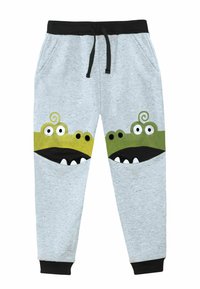 Pantaloni grigi in felpa con cintura e polsini neri, caratterizzati da design a faccia di mostro verde e nera sulle tasche. Texture morbida con motivo a macchie.
