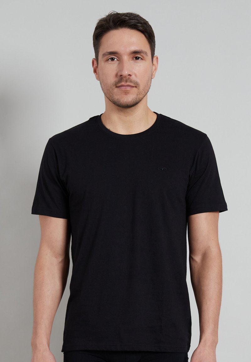 Black crew-neck t-shirt made of cotton, featuring short sleeves and a small embossed logo on the left chest area. Smooth texture.