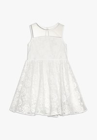 Vit spetsklänning med ärmlös design, texturerat tyg med blommönster och en enfärgad överdel. Kjol med vidd och foder.