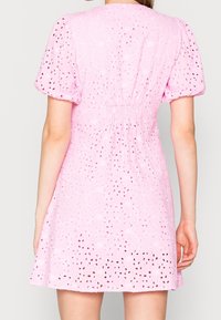 Růžové krátké šaty s nabíranými rukávy, vyrobené z broderie anglaise. Obsahují květinové výřezy a sklady v pase.