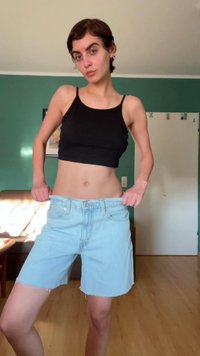 Calções de ganga azul claro com bainha desfiada, apresentados com um top cropped preto. Costuras visíveis e bolsos frontais.