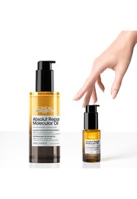 Aceite Molecular Absolut Repair de L'Oréal en dos tamaños: botella ámbar grande con bomba negra y botella ámbar pequeña al lado, ambas con etiquetas.