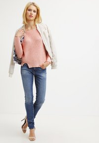 Valkoinen vaaleanpunainen neule, vaaleanbeige bomber-takki, siniset kapeat farkut ja nudet nilkkaketjuhaihkohousut. Suorat pinnat sekä rento istuvuus.