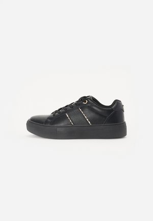 Baskets de sport noires avec une tige en cuir lisse, une semelle en caoutchouc et un détail de rayures contrastantes. Elles sont dotées de lacets traditionnels et d'un embellissement minimal.