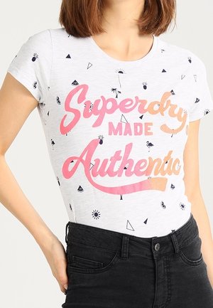Camiseta de algodón blanca con mangas cortas, que presenta un diseño gráfico en texto en rosa y naranja que dice "Superdry MADE Authentic" y pequeños patrones geométricos dispersos.