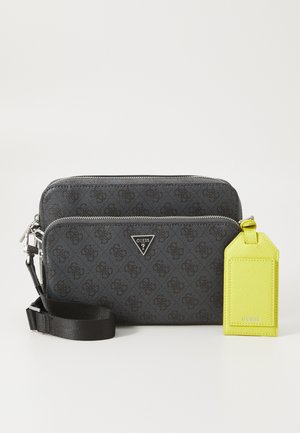 Black patterned crossbody bag with a textured finish, featuring a silver logo, zip compartments, and a detachable bright yellow tag.