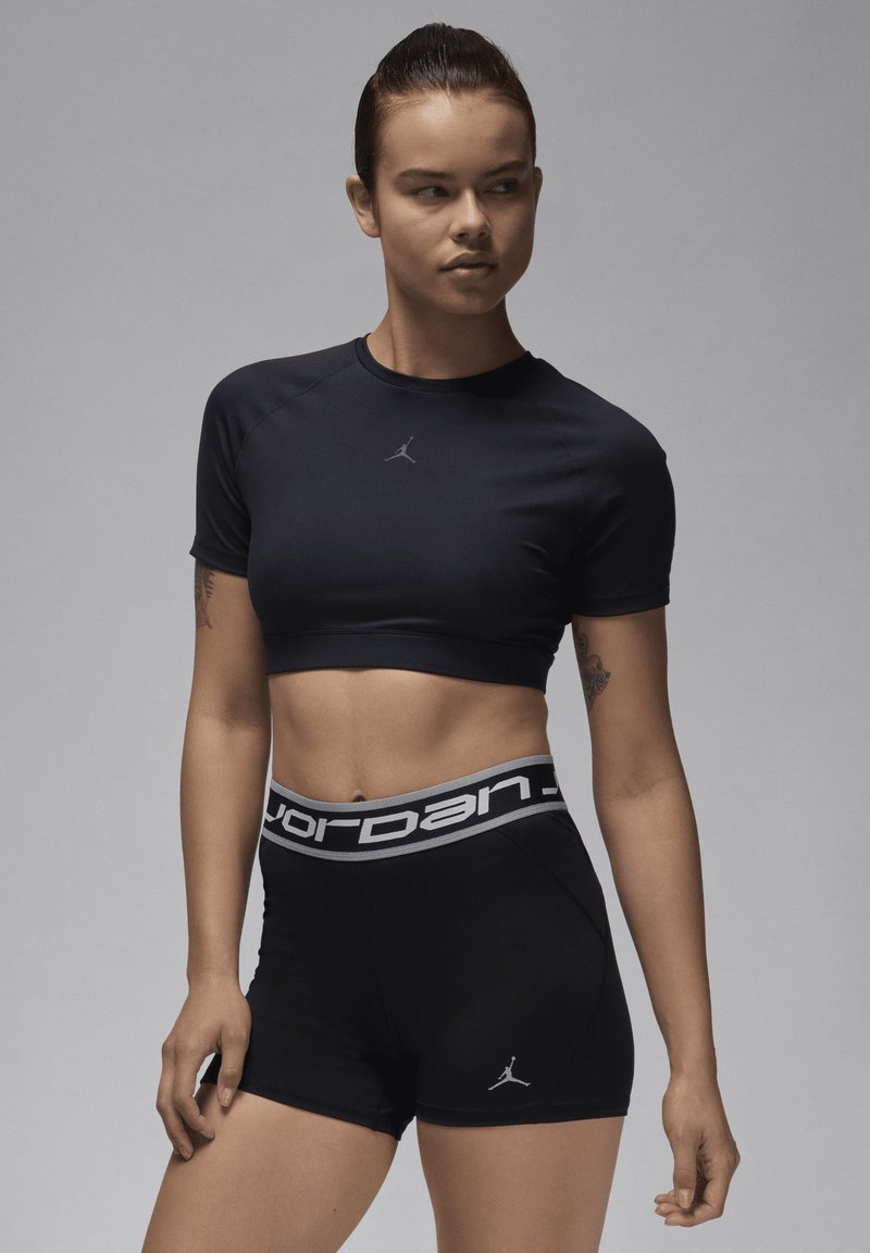 Svart treningstopp med kort erm og enkle detaljer, prydet med Jordan-logoen, samt matchende høyt midjeshorts med Jordan-elastisk midjebånd.