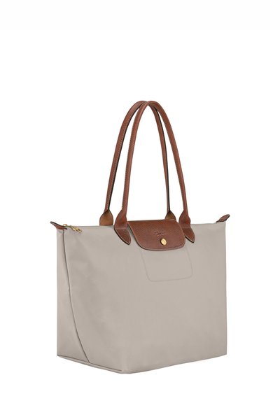 Beige Nylon-Einkaufstasche mit braunen Lederakzenten und Griffen, ausgestattet mit einem Klappverschluss und goldfarbigen Metallakzenten.