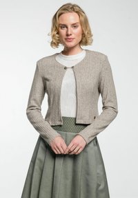 Beige gestrickte Strickjacke mit Rippmuster, cropped Länge, Rundhalsausschnitt und silberner Knopfverschluss, darüber getragen über einem weißen Spitzenoberteil und einem grünen Rock.