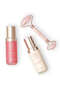 Due flaconi di siero con dettagli dorati: uno rosa etichettato "Siero Notturno per il Recupero della Pelle", uno bianco etichettato "Siero Giornaliero per la Luminosità della Pelle", più un rullo di giada rosa.