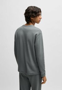 Grijze lange mouw top gemaakt van textuurmateriaal, met een ronde hals, een ruime pasvorm en zichtbare stikdetails op de naden.