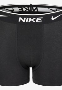 Črne moške bokserice iz mehkega materiala. Imajo prilegajoč dizajn, elastičen pas z belim logotipom "NIKE" in podrobno šivanje.