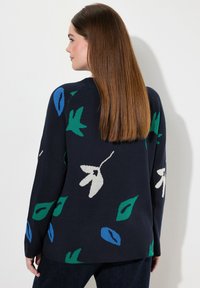 Maglione navy con un motivo floreale in verde, blu e bianco. Tessuto morbido e vestibilità rilassata, con maniche lunghe e scollo rotondo.