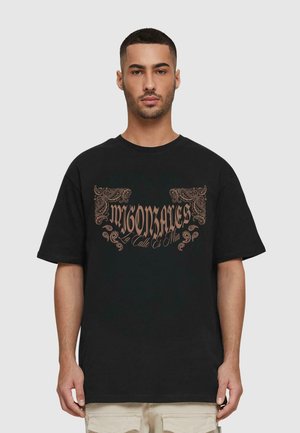 Black cotton short-sleeve t-shirt featuring copper-colored graphic text with ornate decorative accents, round neckline, relaxed fit.