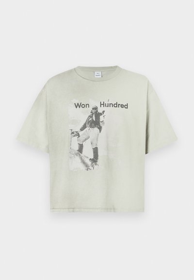 Ανοιχτό πράσινο κοντομάνικο μπλουζάκι με γραφικό τύπωμα ενός άνδρα σε vintage ρούχα και το κείμενο "Won Hundred". Φτιαγμένο από μαλακό βαμβάκι.