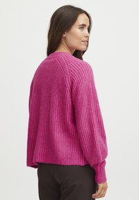 Knitted sweater in bright pink with a textured design. Features a crew neckline and ribbed cuffs, offering a relaxed fit.