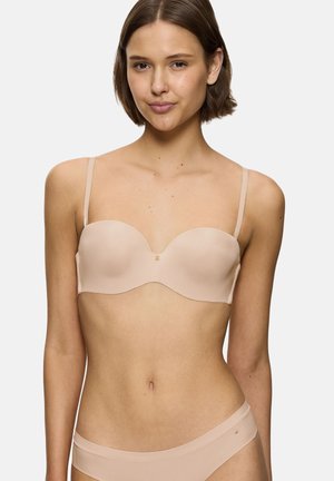 Nude-värinen olkaimeton rintaliivit, joissa on sileät, muotoillut kupit, tukevat kaaritangot ja hienovarainen logokoriste. Säädettävät olkaimet ja saumaton muotoilu mukavuutta varten.