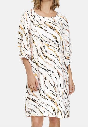 Kortærmet kjole i hvidt stof med et hvirvlende mønster af sorte, ferskenfarvede og brune striber. Løs pasform med rund halsudskæring.