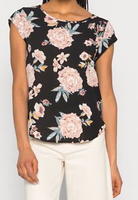 Blusa floreale con sfondo nero, caratterizzata da rose rosa e foglie blu. Maniche corte, scollo rotondo e vestibilità morbida.