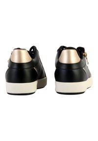 Baskets en cuir noir avec un accent doré contrastant sur le talon et une semelle en caoutchouc blanche, présentant une texture lisse et un design minimaliste.