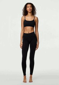 Melnā pusauguma krekla un augsto vidukļu legingu komplekts, kas izgatavots no elastīga auduma. Vienkāršs dizains, pieguļošs siluets un gluda tekstūra. Nav rakstu vai akcentu.