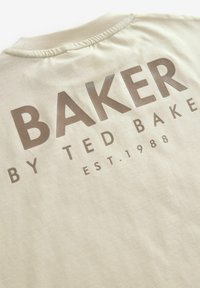 Beżowy bawełniany t-shirt z dużym brązowym napisem "BAKER BY TED BAKER EST. 1988". Krótki, okrągły dekolt o gładkiej fakturze.