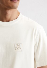 Korte mouwen crème t-shirt van zacht katoen, met een vierkant logo met "MOP" in een lichtbruine kleur op de linkerkant van de borst.