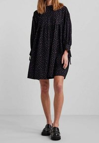 Černé šaty s dlouhými rukávy, nařaseným pasem a barevnými puntíky. Mají šňůrkové detaily na rukávech a volný střih.