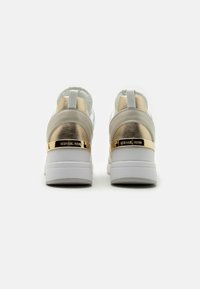 Białe sneakersy o smukłym designie z metalicznym złotym akcentem na pięcie i teksturowanym beżowym paskiem. Gładka gumowa podeszwa.