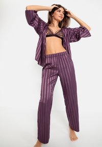 Paarse satijnen pyjama set met een gestreept ontwerp, korte mouwen en een elastische band aan de broek. Kantafwerkingen op de beha.