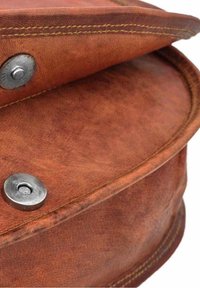 Hnědá kožená taška s viditelnou strukturou, zaobleným tvarem a kontrastním žlutým prošitím. Má stříbrné zapínání na cvok.