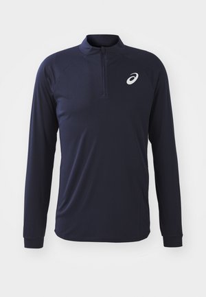 Camiseta deportiva de manga larga en color navy con cuello de media cremallera, textura suave y un pequeño logo contrastante en el lado izquierdo del pecho.