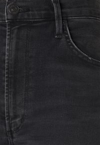 Jeans de mezclilla negra con una textura suave, que cuentan con un bolsillo frontal y un cierre de botón metálico. Costuras sutiles a lo largo de las costuras.