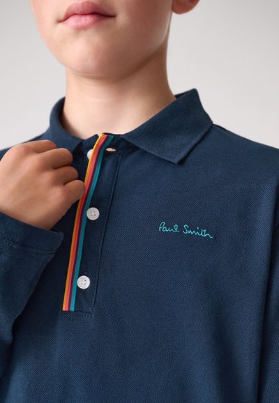 Tengeri kék galléros póló texturált anyagból, háromgombos elülső résszel, többszínű csíkos díszítéssel és fehér gombokkal, hímzett logóval.