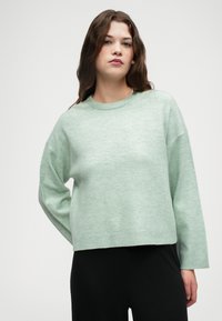 Pull en tricot léger de couleur vert menthe, avec un col rond et des épaules tombantes ; poignets et ourlet côtelés ; texture douce.