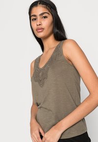 Top de alças verde oliva com um design em renda texturizada na gola, feito de um tecido suave e leve, apresentando um corte descontraído e sem mangas.