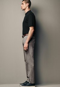 Must must shirt, heledad hallid püksid, pruun vöö ja mustad tossud. Omab sirget lõiget, peente tekstuuride ja sujuva kangaga.