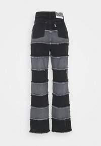 Svarta och grå lapptäcksjeans med en vid bendesign, fransade kanter och hög midja med en märkesskylt på baksidan.