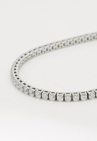 Collier en argent comportant plusieurs strass ronds et transparents disposés en motif de grille, avec un design élégant et flexible.
