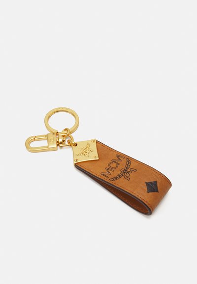 Portofel de chei din piele maro, cu un atașament metalic auriu. Prezintă un logo embosat și accente, având o formă rectangulară și detalii contrastante.