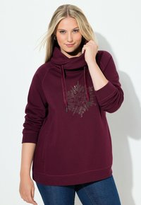 Felpa burgundy con cappuccio e collo a scialle, caratterizzata da un motivo di fiocchi di neve in strass e tasca anteriore; realizzata in un morbido tessuto testurizzato.