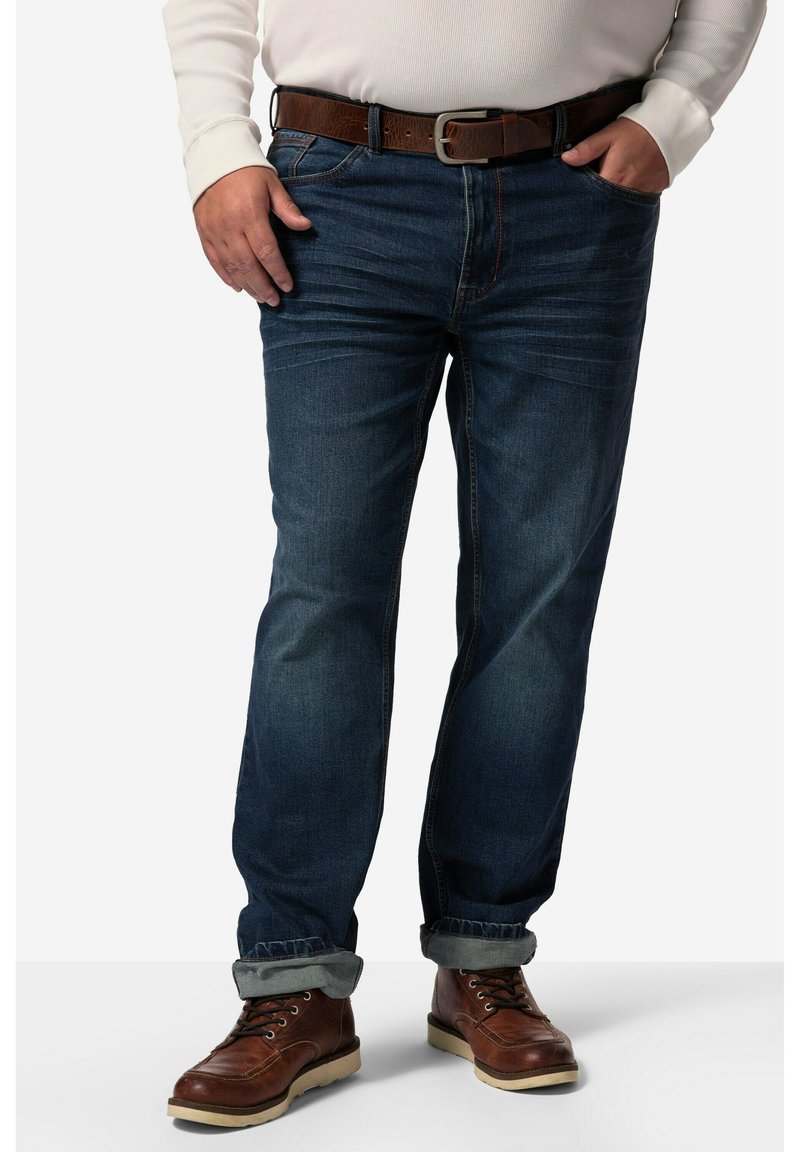 Jeans in denim blu scuro con un design a gamba dritta, dotati di risvolto. Abbinati a stivali marroni con lacci e a una cintura marrone.