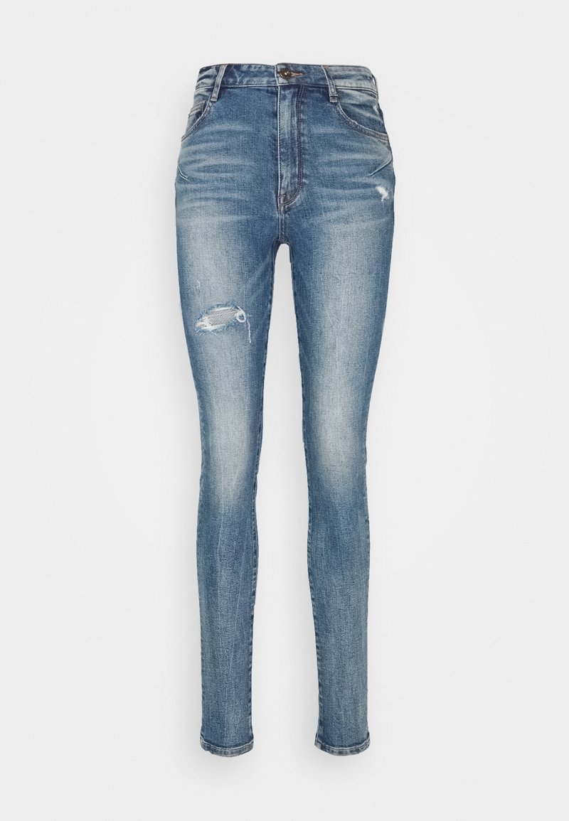 Vaqueros ajustados de denim azul medio, con cintura alta, detalles desgastados con un desgarro en el muslo izquierdo y una forma ceñida.